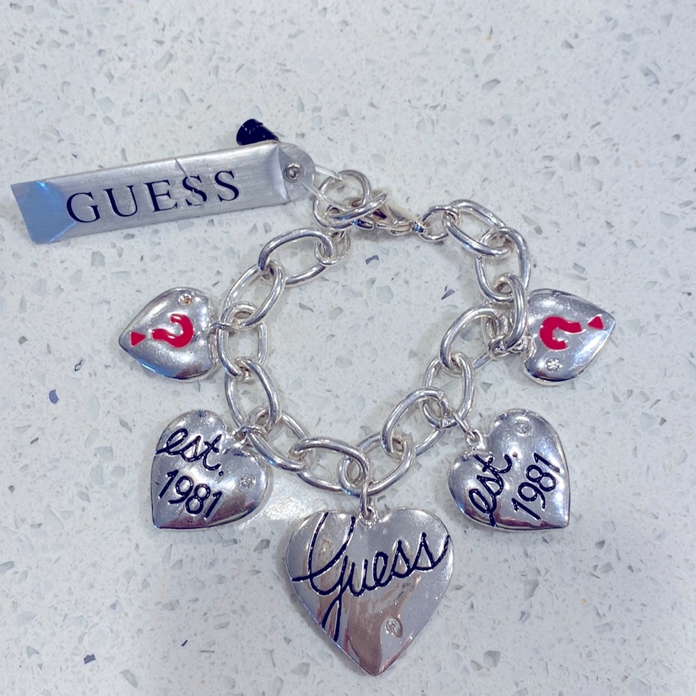 Guess silver tone chain link charm bracelet with hearts and crystal charms.